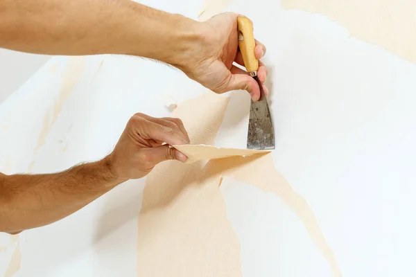 Removing old wallpaper with a putty knife during wall preparation for an interior painter in Worthington, OH.
